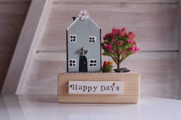 Happy Days Decorative model house with a tree and the text "Happy Days" on a wooden base.