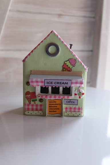 Ice Cream Anyone? A small green decorative house with an ice cream shop facade and a pink awning.